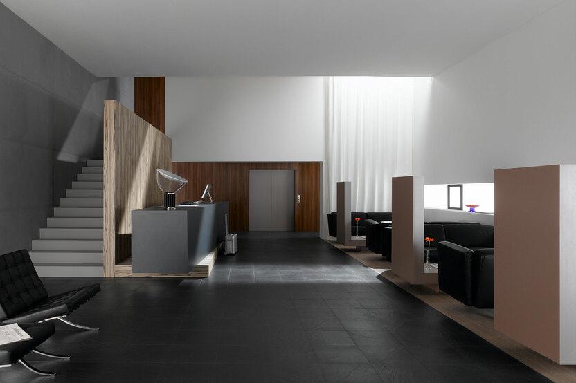 Hotelappartment Untergeschoss mit Holzmobiliar, dunklem Parkett und Treppenaufstieg