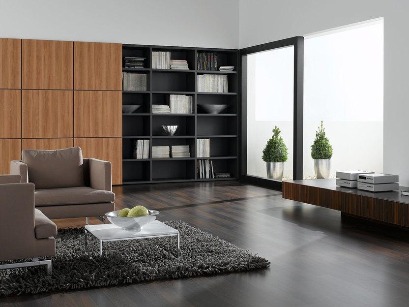 Wohnraumimpression mit verschieden dunklen Holzoberflächen für Einbauschrank, Sideboard und Bodenbelag