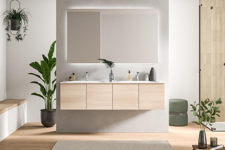 Ein schickes Bad nach Maß mit einem hellen Holzwaschtisch, Doppelwaschbecken und einer großen Spiegelfläche, umgeben von grüner Zimmerpflanze.