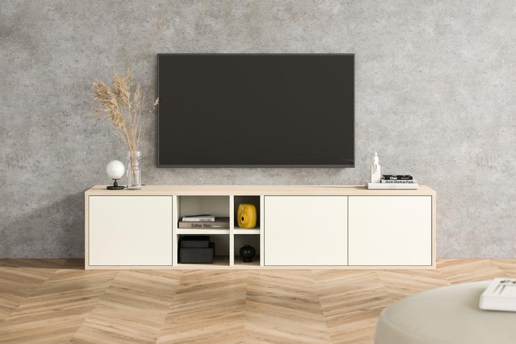 Maßgefertigte Kommode in Creme mit offenen Fächern und gelben Akzenten, unter einem Wandfernseher, vor einer Betonwand im urbanen Wohnzimmer.
